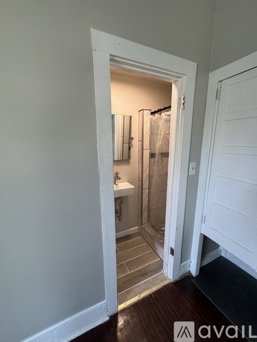 A bathroom with a glass shower door and a white door.