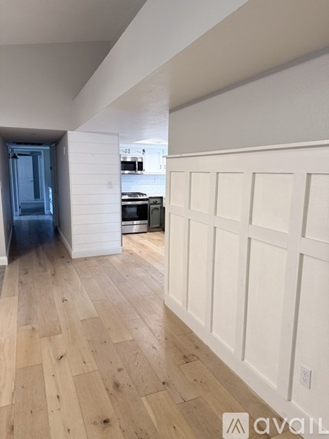 A kitchen with white cabinets and a wooden floor.