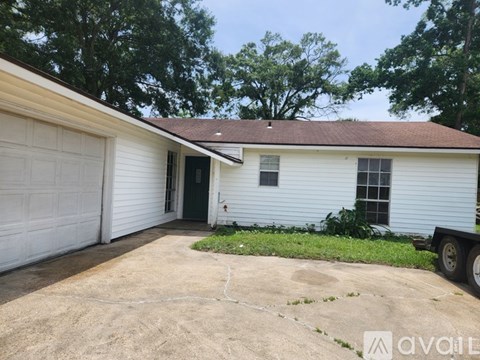 A white house with a brown roof and a garage door is available for rent.