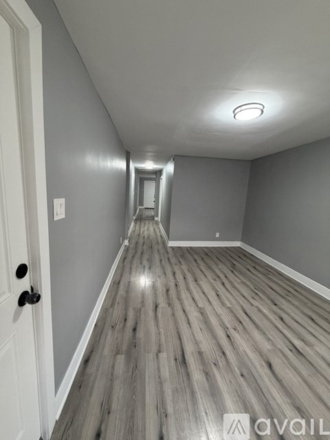 A hallway with wooden floors and a white door.