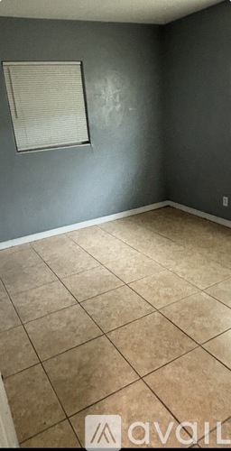 A room with a tile floor and a window with blinds.