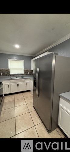 A kitchen with a stainless steel refrigerator and white cabinets.