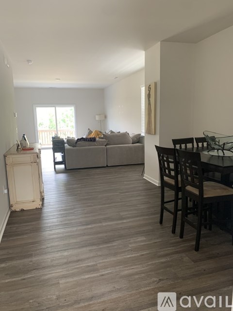 A living room with a grey couch, a wooden floor, and a dining table with chairs.