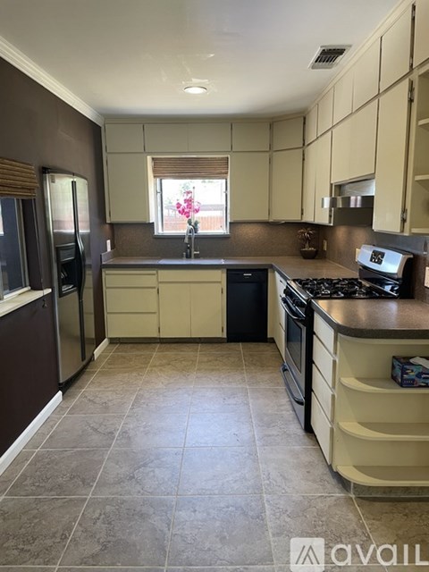 A kitchen with brown cabinets and a black dishwasher.