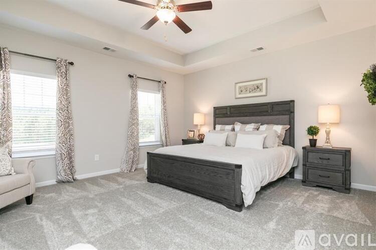 A bedroom with a large bed, a ceiling fan, and a window with curtains.