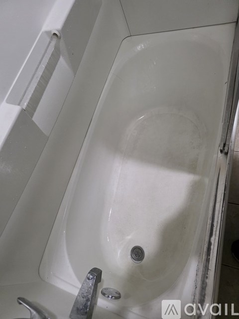 A white bathtub with a silver faucet and a silver handle.