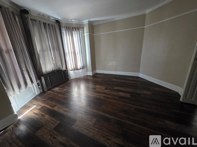 A room with wooden flooring and a radiator under the window.