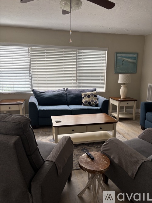 A living room with a grey couch, a brown chair, and a white coffee table.