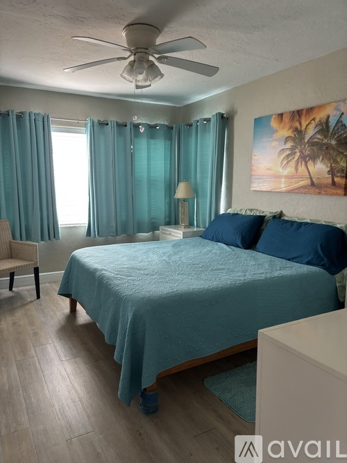 A bedroom with a bed, chair, and painting on the wall.