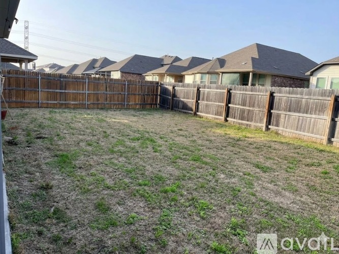 A backyard with a wooden fence and grassy area.