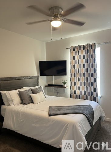A bedroom with a large bed and a flat screen TV mounted on the wall.