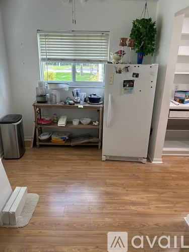 A kitchen with a white fridge and wooden floors.