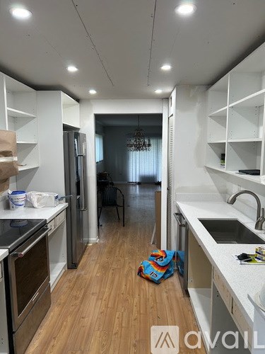 A kitchen with white cabinets and a wooden floor.