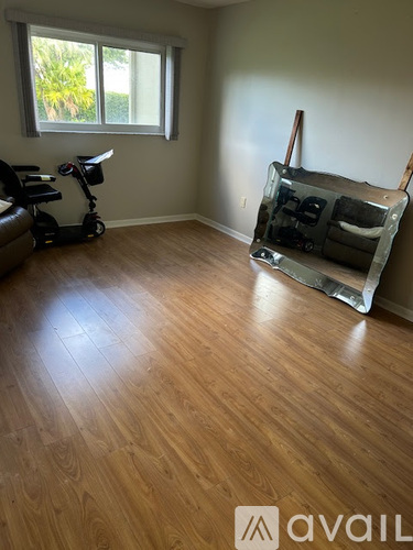 A room with wooden flooring and a window with a view of trees.