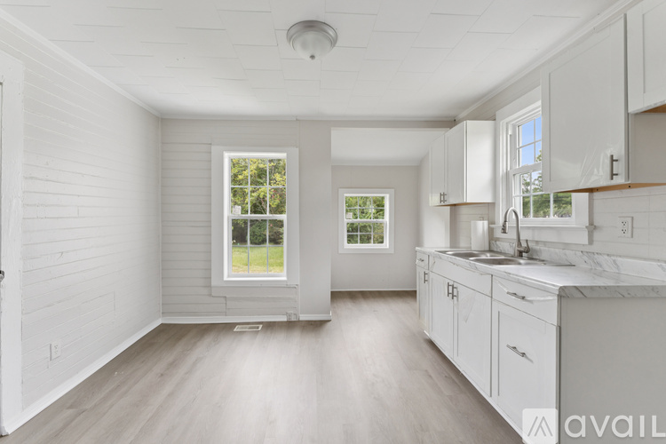 A spacious kitchen with white cabinets and a marble countertop.