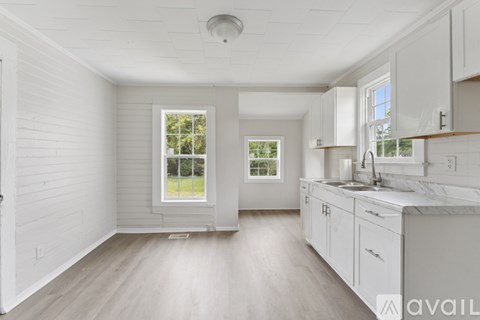 A spacious kitchen with white cabinets and a marble countertop.