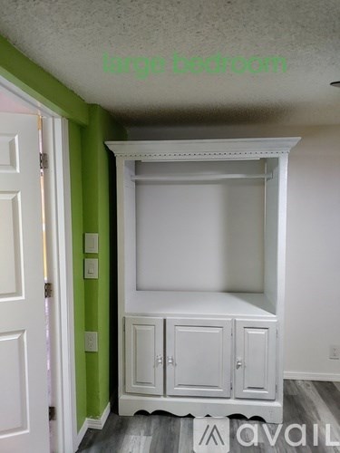 A large bedroom with a white wardrobe and a door.