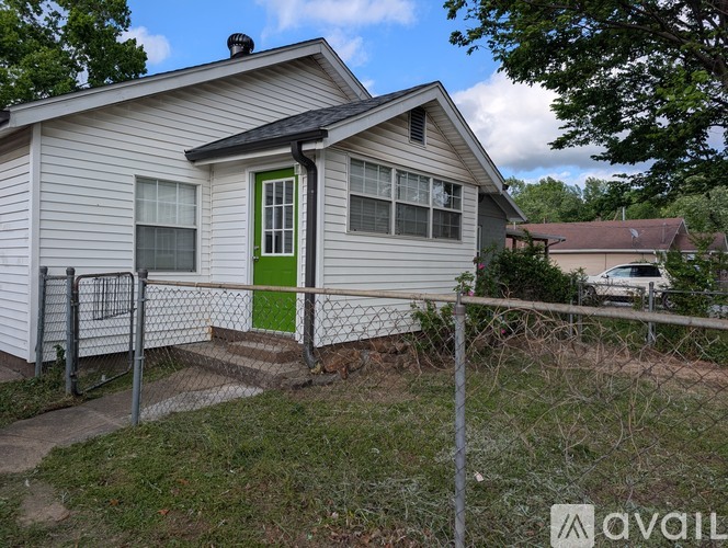A house with a green door is surrounded by a fence.