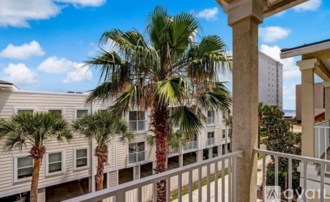 A balcony with a white railing and a palm tree in front of a building.