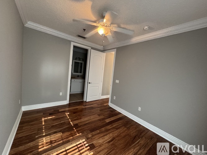 A room with a ceiling fan and wooden flooring.