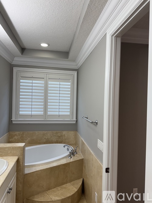 A bathroom with a tub, sink, and window with blinds.