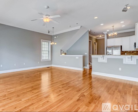 A spacious room with wooden floors and a ceiling fan.