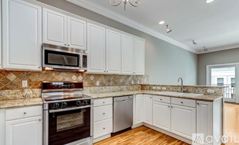 A kitchen with white cabinets and a granite countertop.