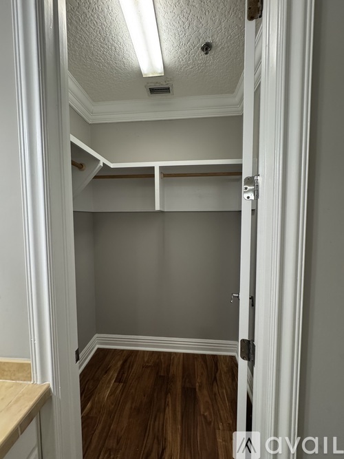 A small, empty room with a wooden floor and white walls.