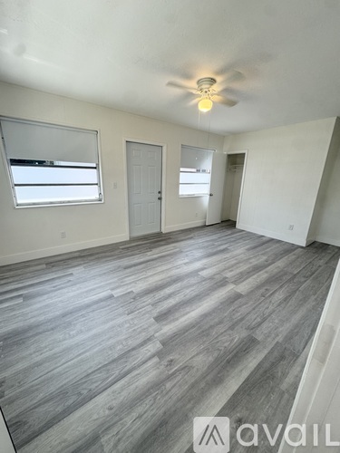 A room with grey flooring and a ceiling fan.