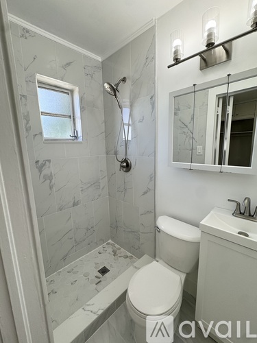 A white toilet is in a marble tiled bathroom.