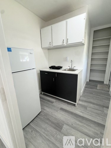 A kitchen with a white fridge, black countertops, and white cabinets.