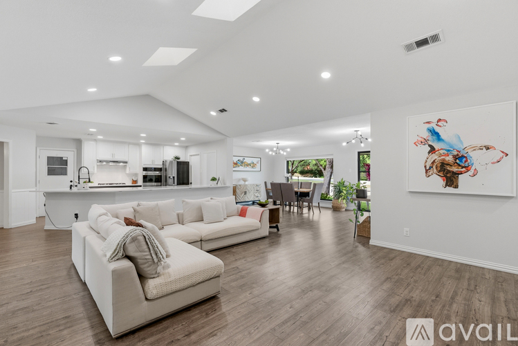 A living room with a white couch and a painting on the wall.