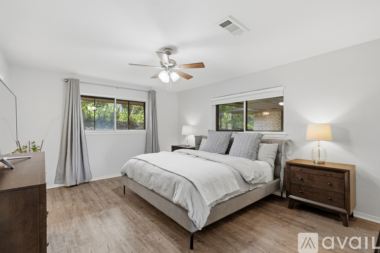A bedroom with a large bed, a ceiling fan, and a nightstand with a lamp.