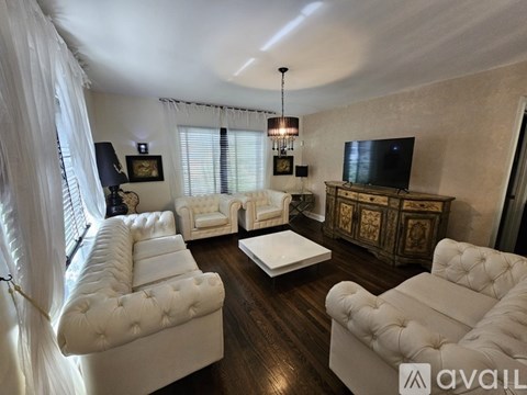 A living room with white furniture and a flat screen TV.