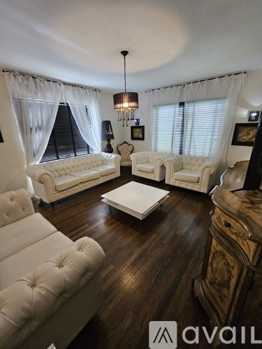A living room with white furniture and a chandelier.