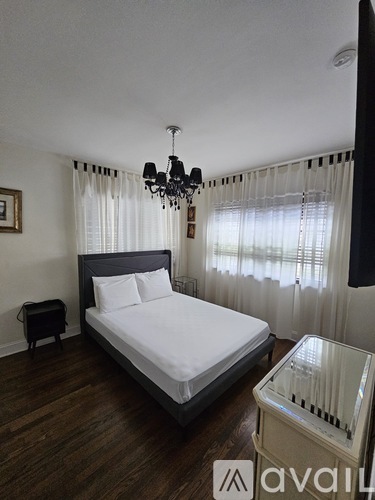 A bedroom with a large bed and a chandelier.