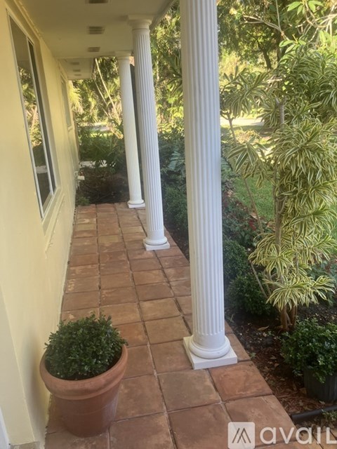 A porch with columns and a potted plant.