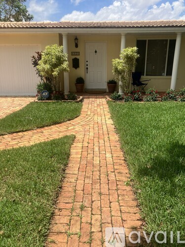 A house with a white door and a brick pathway leading to it.