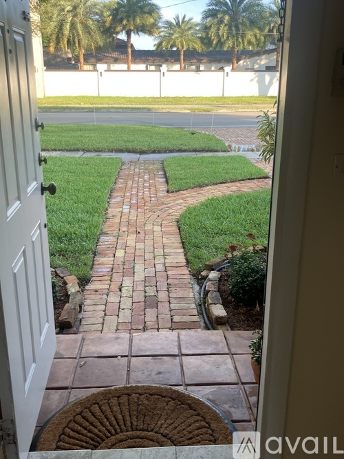 A white door with a brick pathway leading to a grassy area.