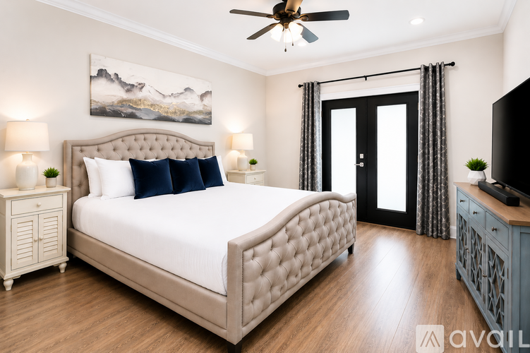 A bedroom with a large bed, a ceiling fan, and a painting on the wall.