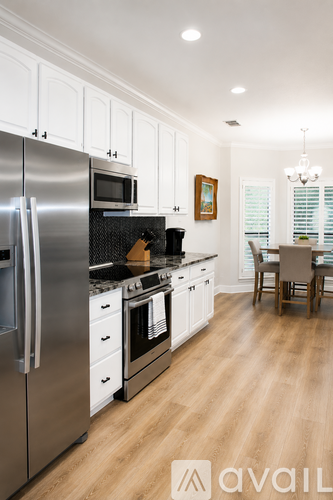 A modern kitchen with stainless steel appliances and wooden floors.