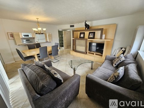 A living room with grey couches and a wooden entertainment center.