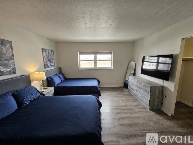 A bedroom with two beds and a television in the corner.