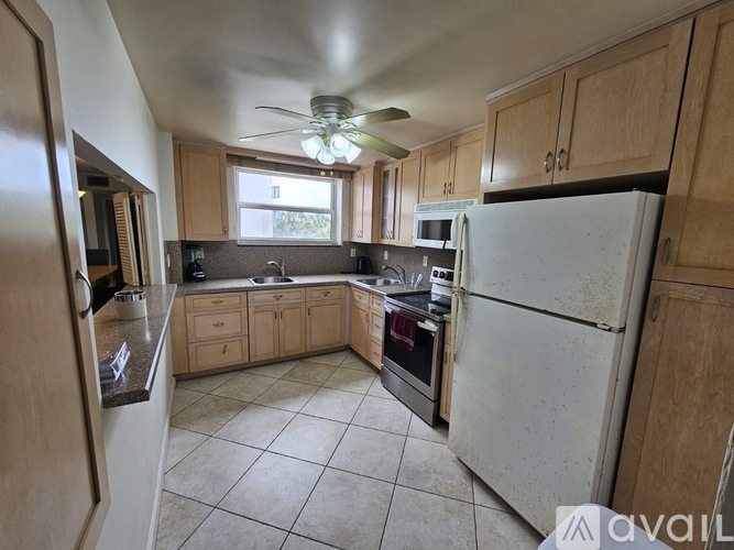 A kitchen with a white refrigerator, wooden cabinets, and a ceiling fan.