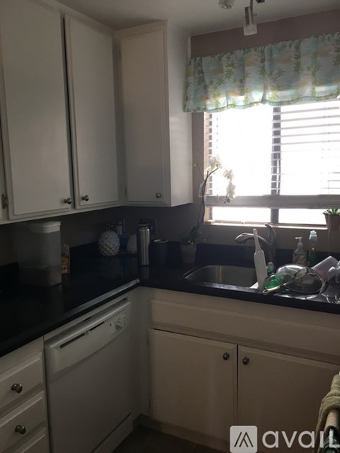 A kitchen with white cabinets and a black countertop.