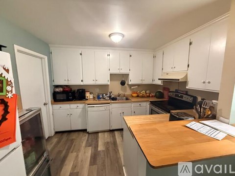 A kitchen with white cabinets and a wooden countertop.