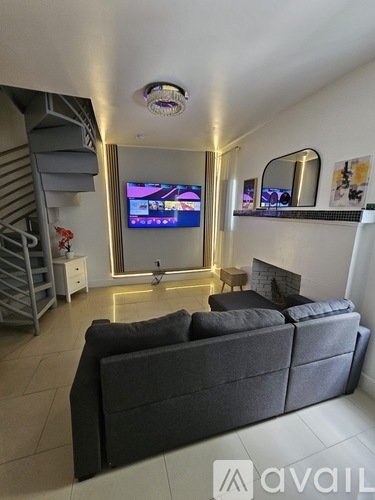 A living room with a grey couch and a television on the wall.