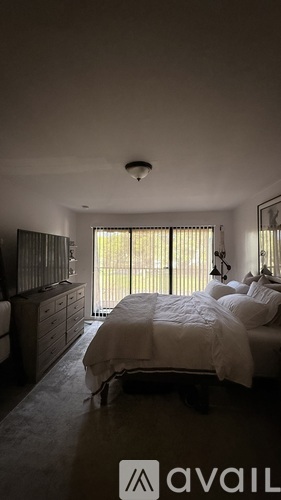 A bedroom with a bed, dresser, and window with blinds.