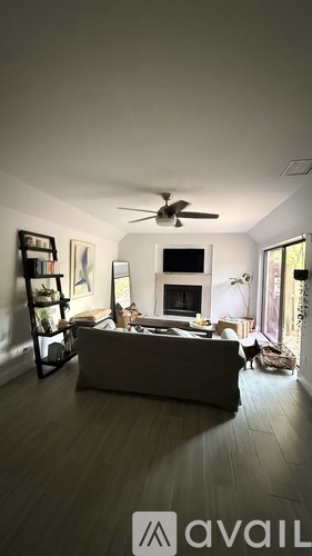 A living room with a couch, a television, a bookshelf, and a ceiling fan.