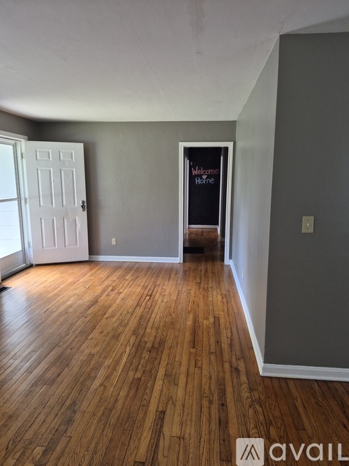 A room with wooden floors and a sign that says "Welcome Home".